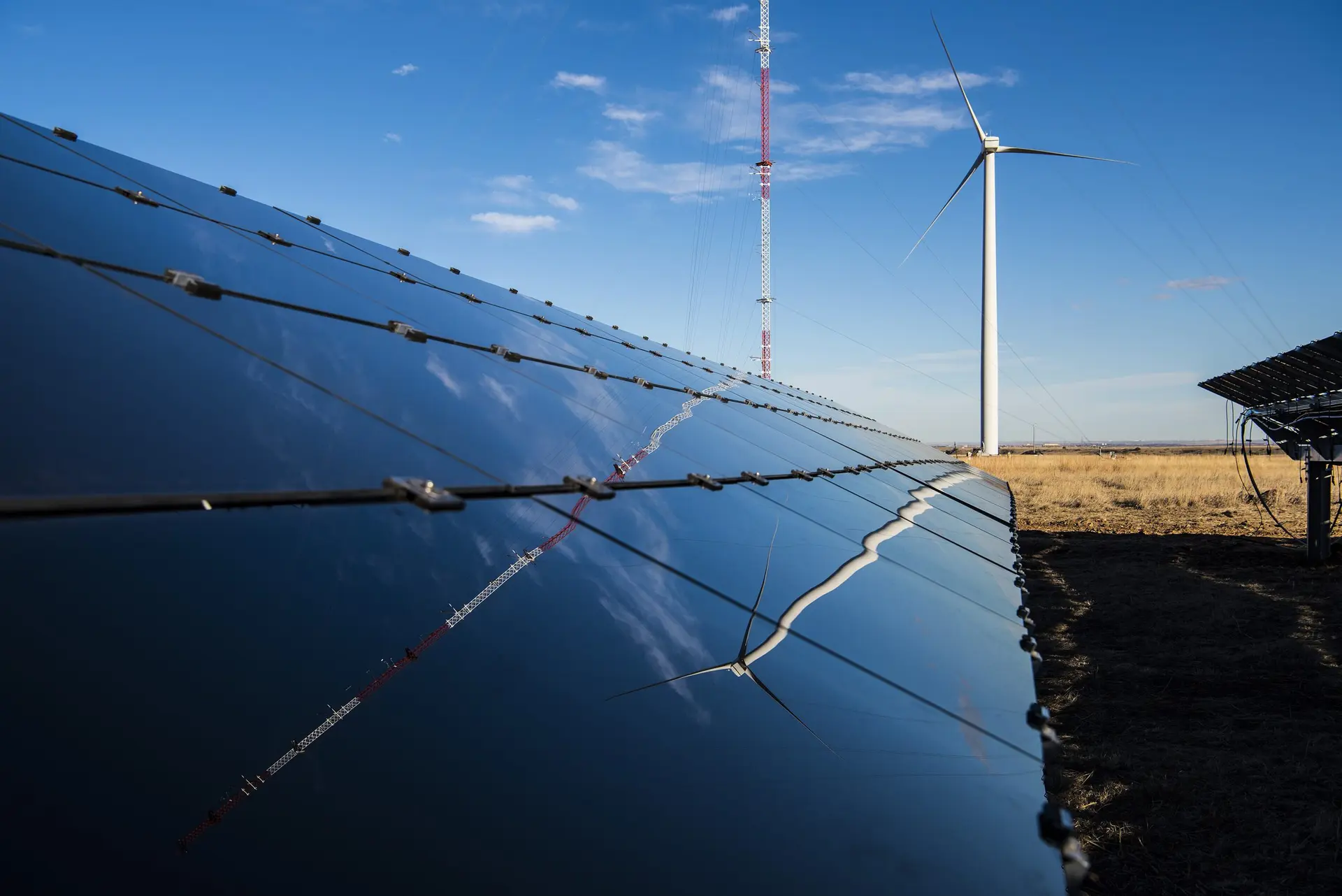Rows of solar panels with a wind turbine